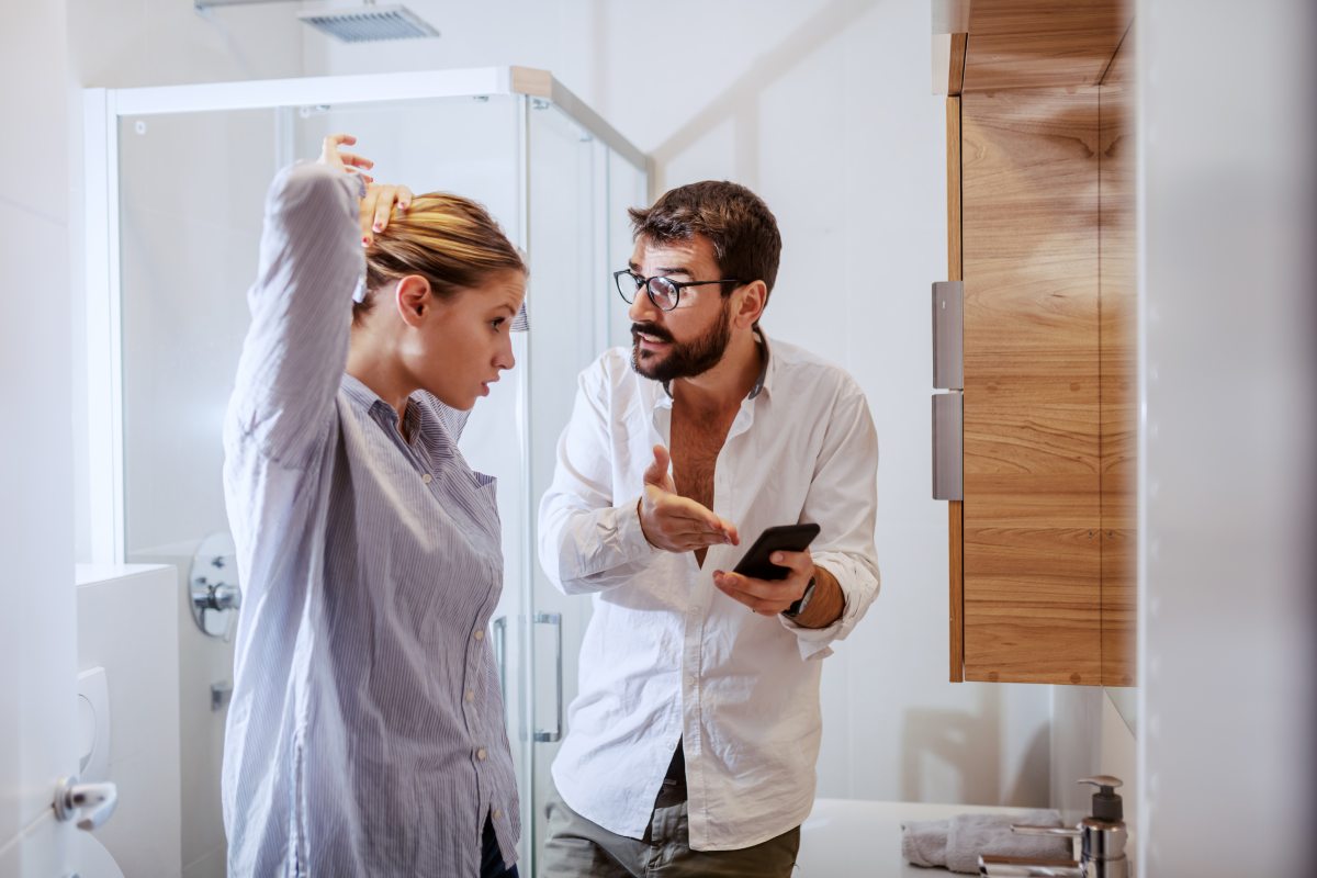 man holding smart phone and showing message to his wife